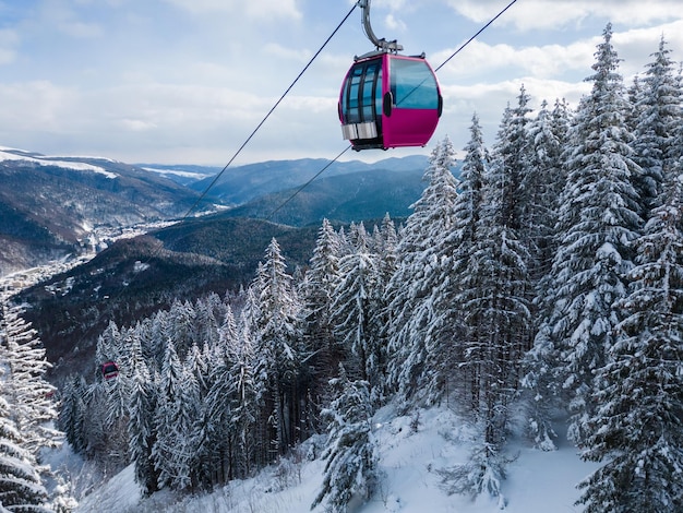 Gôndola moderna do elevador de esqui contra a floresta de abetos coberta de neve e montanhas