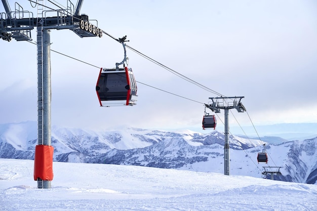 Góndola de teleférico en la estación de esquí con montañas nevadas en el fondo Remonte moderno con funitels y torres de apoyo en lo alto de las montañas en el día de invierno No hay gente