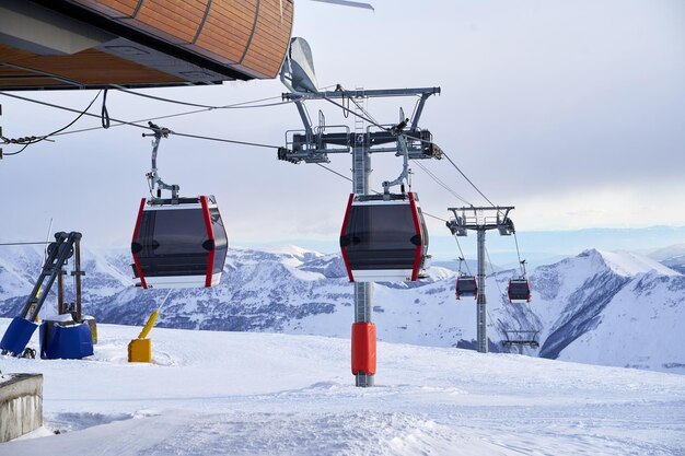 Foto góndola de teleférico en la estación de esquí con montañas nevadas en el fondo remonte moderno con funitels y torres de apoyo en lo alto de las montañas en el día de invierno no hay gente