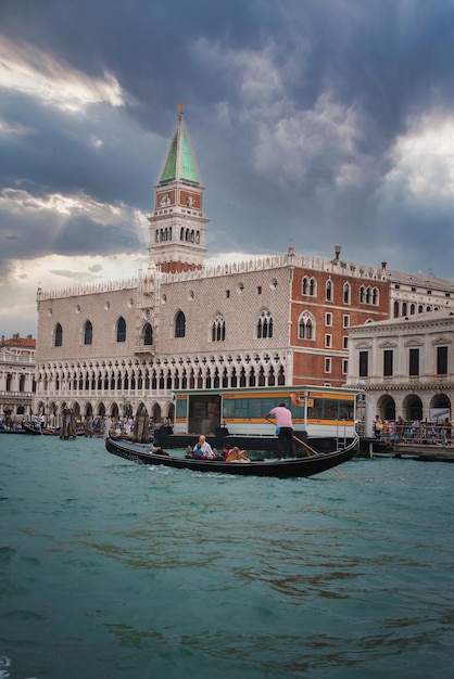 Gôndola veneziana tradicional com ocupantes e igreja no fundo na água em Veneza