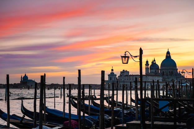 Gôndolas no Grande Canal e na Basílica de Santa Maria della Salute ao pôr do sol em Veneza, Itália. Destino turístico famoso. Conceito de viagens e férias