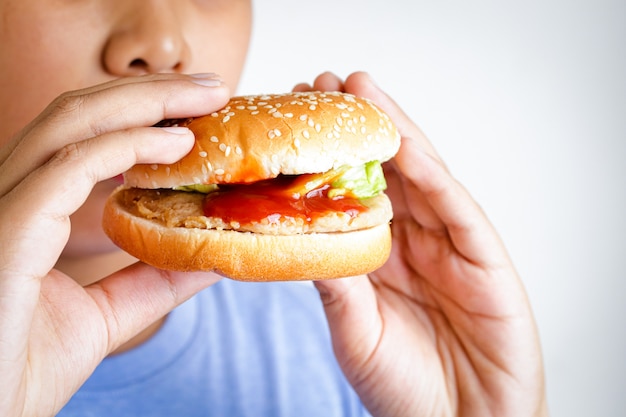 El gordo asiático come hamburguesas. Conceptos alimentarios que causan problemas de salud física en los niños. Causan enfermedades fáciles como la obesidad.