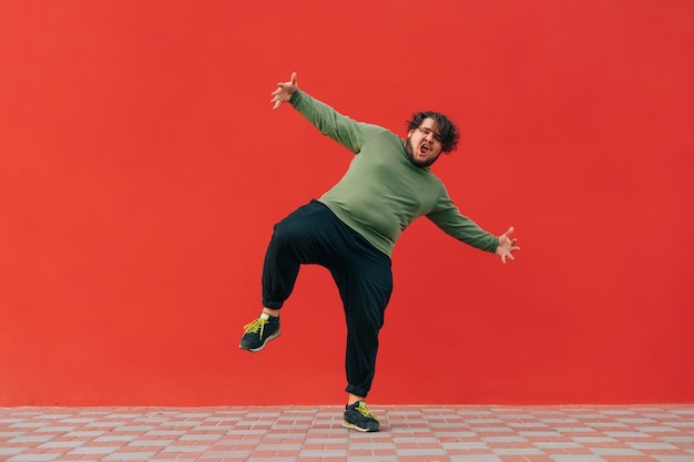 Gordo com cabelo encaracolado dança em um fundo vermelho