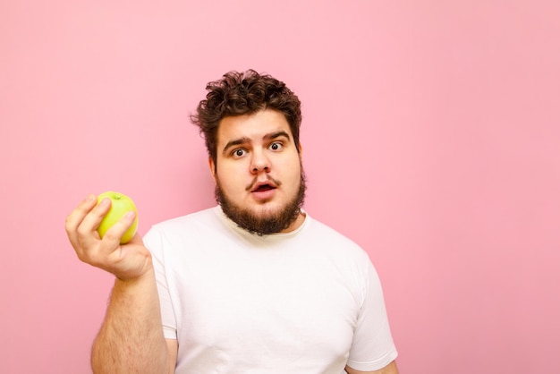 Gordo engraçado com cara de surpresa segura uma maçã na mão isolado