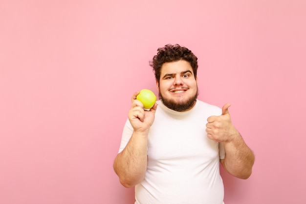 Un gordo gracioso a dieta aislado con una manzana en la mano