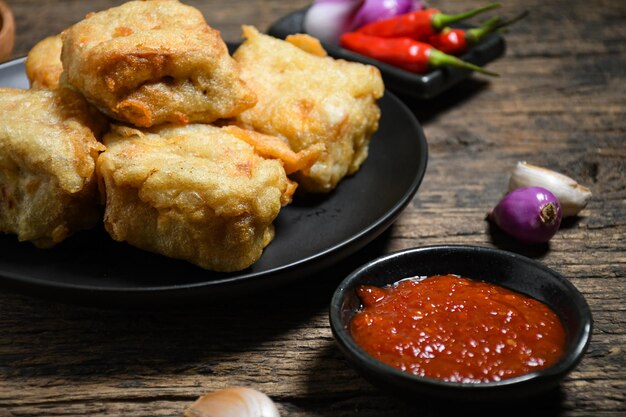 Gorengan oder gebratener Tofu mit Sambal und Chili auf schwarzem Teller und Holztisch