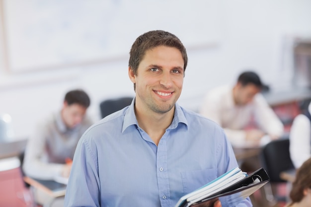 Gorgeous brunette male teacher posando em sua sala de aula