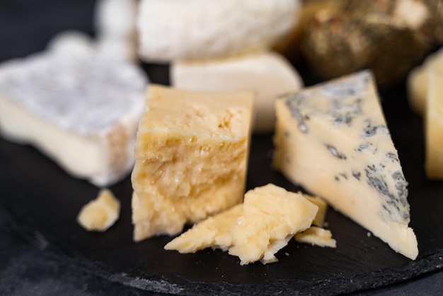 Foto gorgonzola y otros tipos de queso. trozos de diferentes quesos en un plato. un apetitoso manjar gourmet.