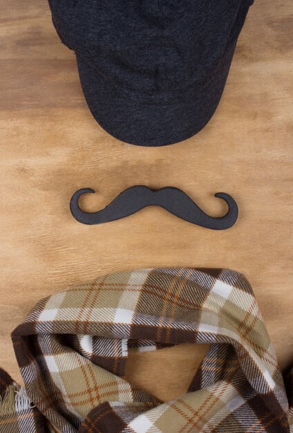 Gorra, bigote negro y bufanda a cuadros