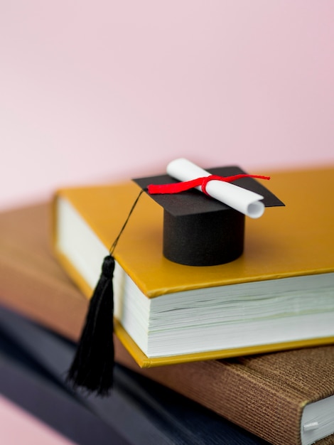 Gorra de graduación de alto ángulo y diploma en diferentes libros