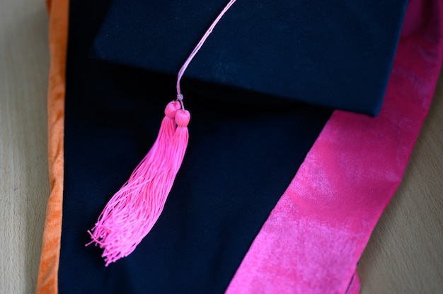 Gorra de graduación, borla negra, amarilla, puesta en un vestido negro.