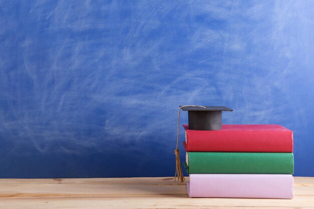 Gorra de graduación con libros en el fondo de la pizarra en el auditorio