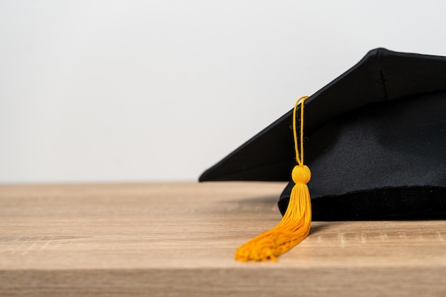 Gorra de graduación negra Nivel universitario colocado en una mesa de madera concepto de graduación