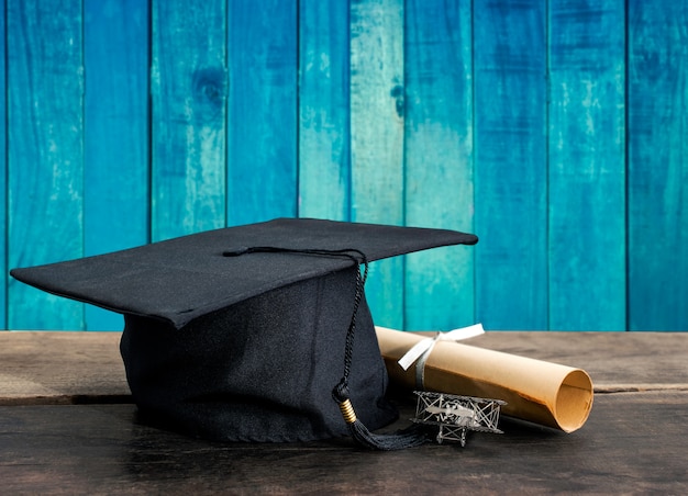 Gorra de graduación, sombrero con papel de grado en la mesa de madera, fondo de madera vintage Vacío listo