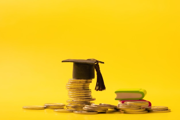 Gorra graduada con monedas sobre fondo amarillo Concepto de ahorro para la educación