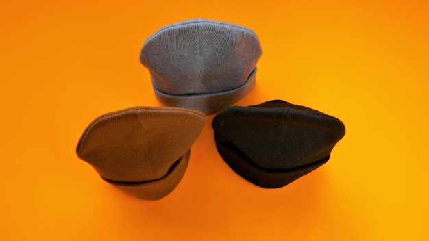 Foto gorro chapéus em um fundo laranja brilhante cinza preto e marrom chapéus de malha chapéus da moda