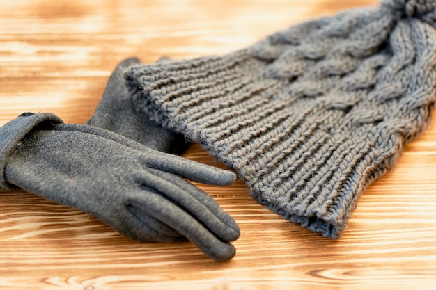Gorro gris y guantes tejidos en una superficie de maderaEl concepto es mantener el calor en otoño o invierno