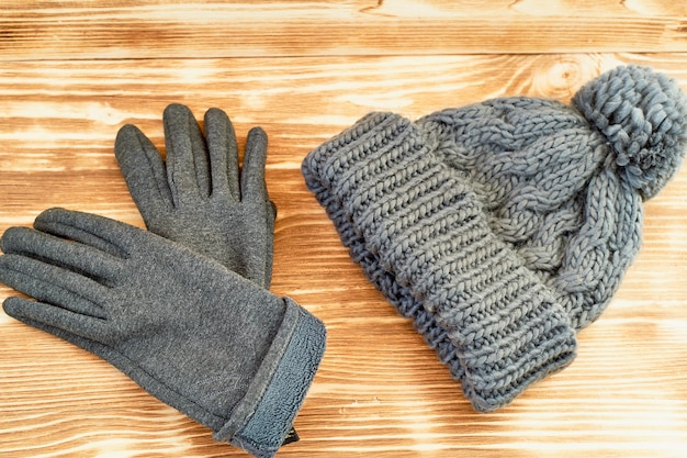 Gorro gris y guantes tejidos en una superficie de maderaEl concepto es mantener el calor en otoño o invierno