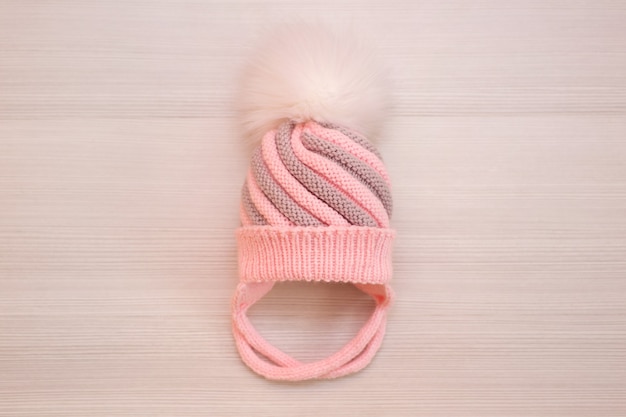 Gorro infantil de malha de lã rosa com pompom, sobre fundo branco
