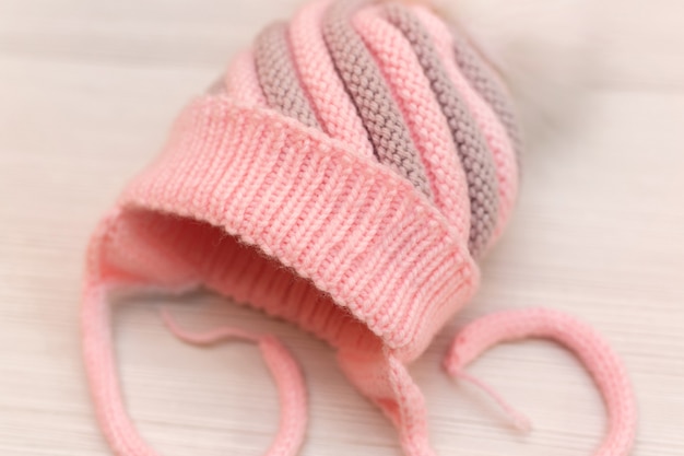 Gorro de lana tejida infantil rosa con pompón, sobre un fondo blanco.