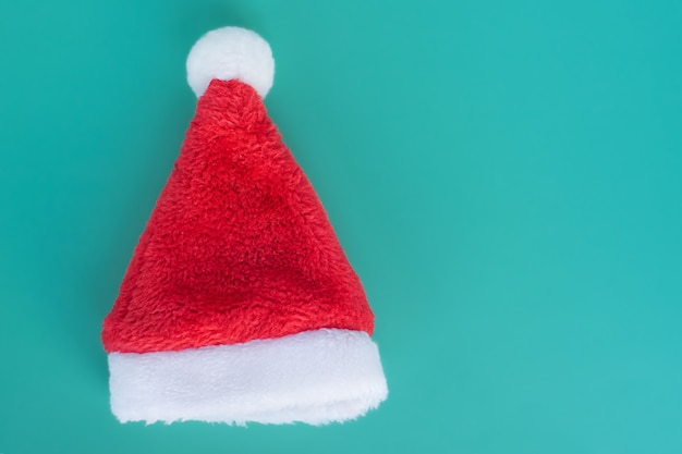 Gorro de Papá Noel esponjoso rojo-blanco sobre un fondo turquesa. Concepto de navidad y año nuevo.