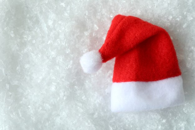 Gorro de Papá Noel rojo sobre fondo de nieve decorativa