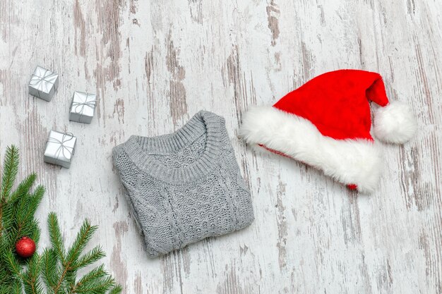 Gorro de Papá Noel y un suéter gris sobre un fondo de madera Concepto de moda