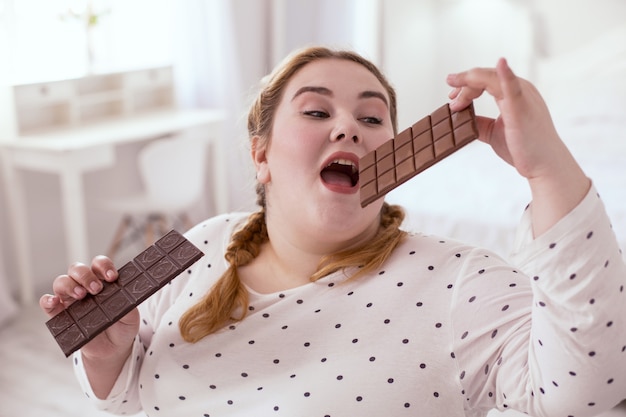 Gosto incrível. jovem encantadora vestindo um macacão branco enquanto prova chocolate