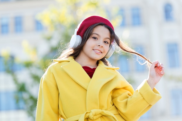 Gosto musical de infância e adolescência. Menina ouvindo música desfrutar de música favorita. Menina com meio urbano de fones de ouvido. Roupa de estilo francês menina criança curtindo música. Influência positiva da música.