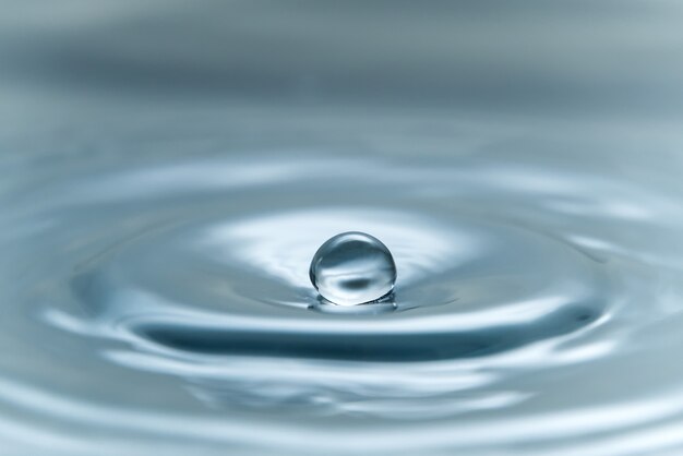 Una gota de agua flotando en el aire antes de golpear la superficie del agua, lo que causará una hermosa foto de primer plano.