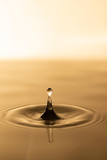 Foto gota de agua gota de agua transparente con ondas circulares gotas de agua salpicadas de amarillo dorado ligeramente borrosas concepto de gota de agua natural y utilícelo como fondo