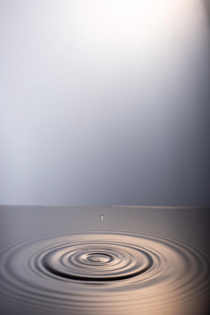 Una gota cae al agua sobre un fondo blanco de gamuza