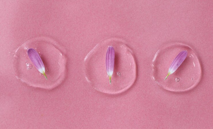 Foto gota cosmética em um close up de fundo rosa com uma pétala conceito elegante de essências orgânicas