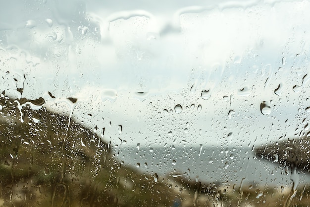 Gota de chuva turva no fundo de vidro do carro, gotas de água na janela do carro