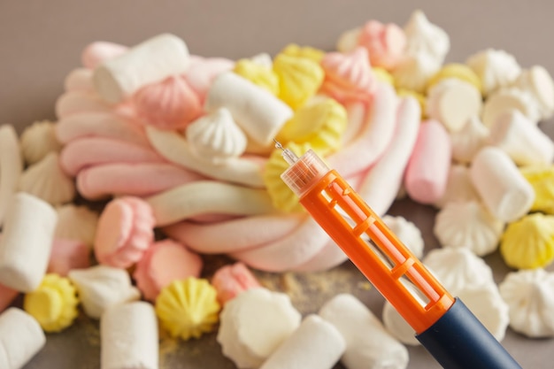 Foto gota de sangue e merengue e marshmallows no conceito de diabetes de fundo vermelho