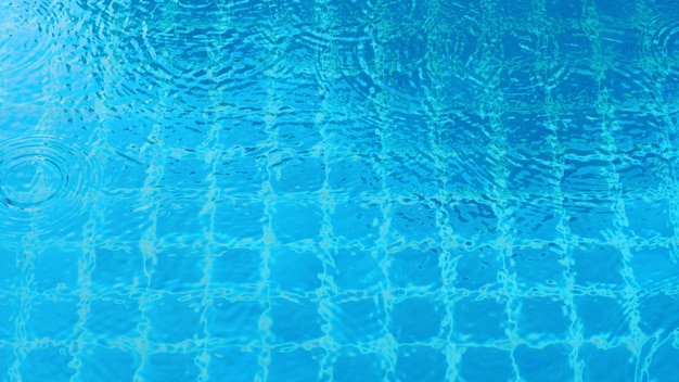 Gota de lluvia cayendo sobre la piscina y la forma ondulada y el reflejo de la luz del sol en la superficie del agua