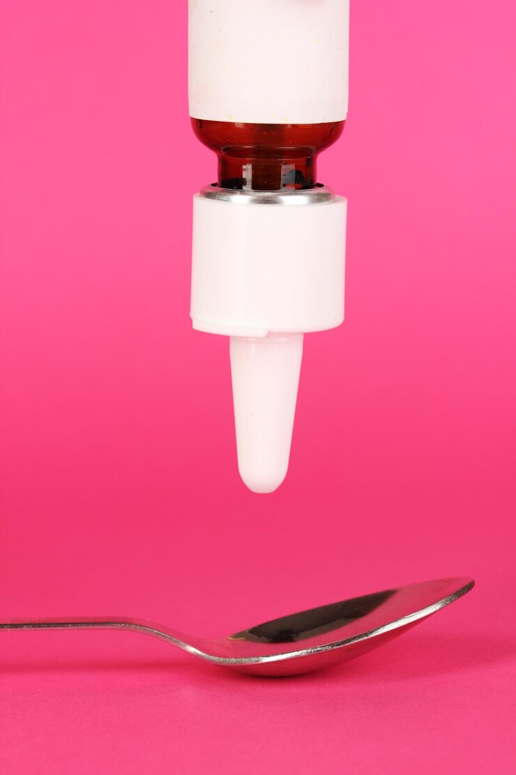 Foto gota médica en cuchara sobre fondo rosa