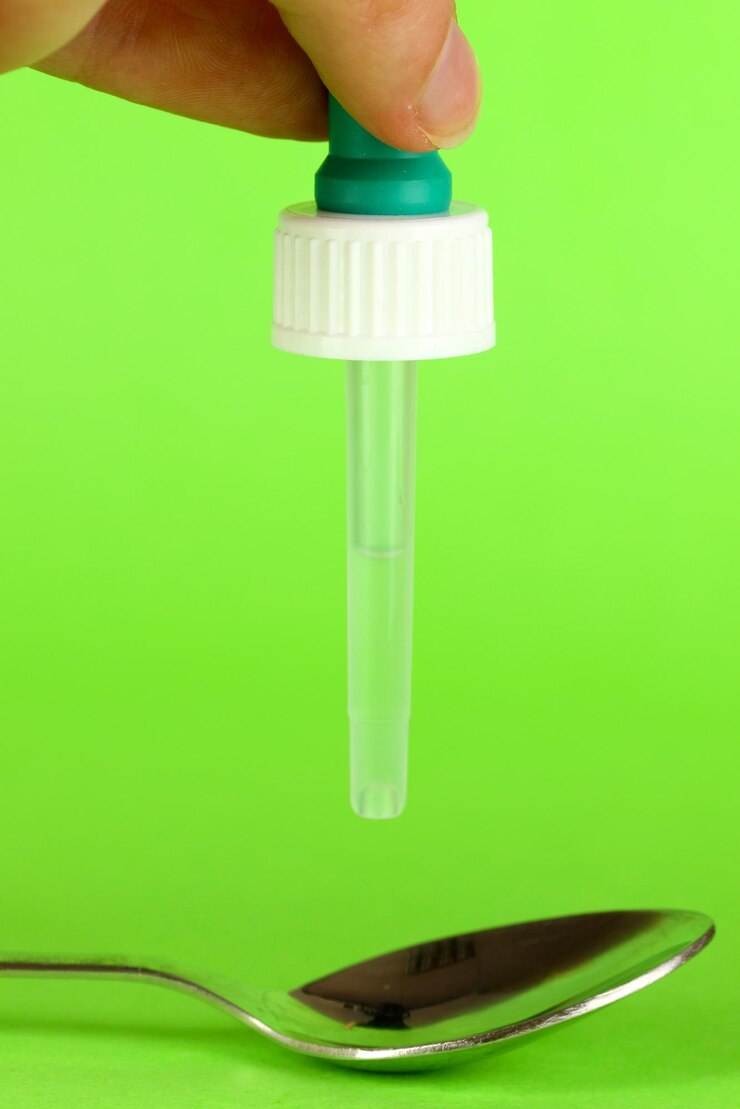 Foto gota médica na colher no fundo verde