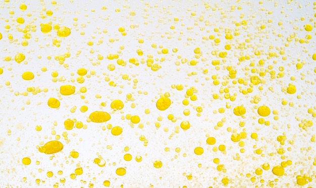 Gotas de aceite aisladas gotas de líquido dorado de aceite en agua sobre un fondo blanco alimentos o cosméticos