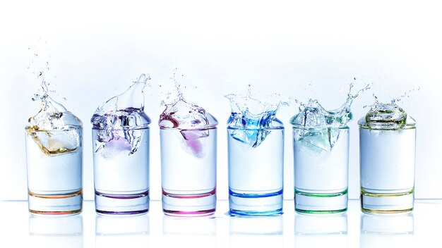 Las gotas de agua de caer un cubo de hielo en un vaso de líquido.