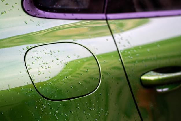 Gotas de agua después de la lluvia en el detalle del coche verde de cerca