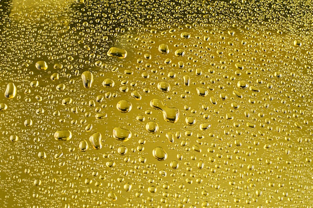 Gotas de agua de fondo abstracto sobre una superficie brillante dorada