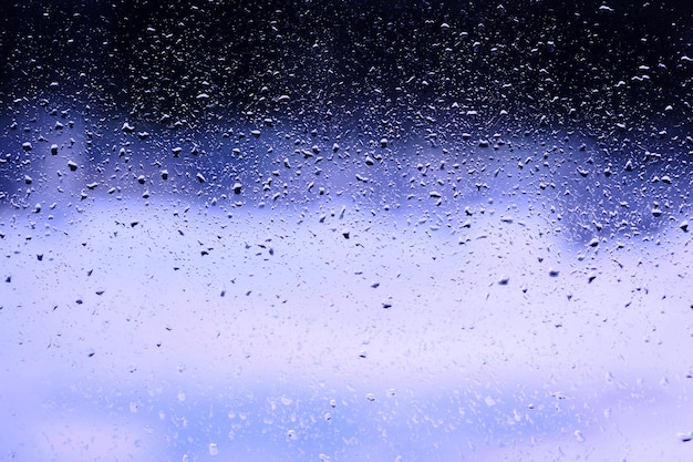 Gotas de agua de fondo azul sobre el vidrio