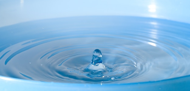 Las gotas de agua gotean sobre un agua azul