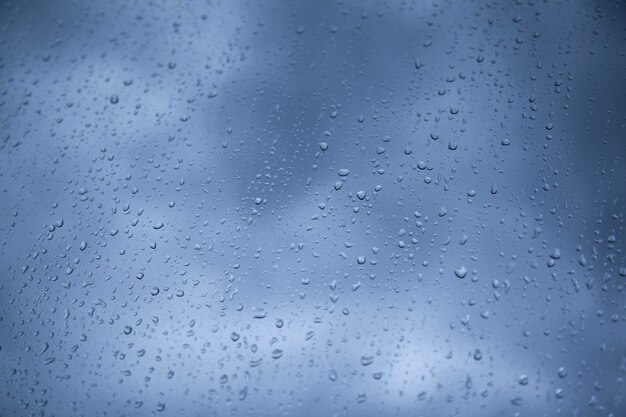 Gotas de agua de lluvia sobre fondo de cristal azul