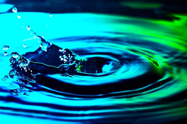 Gotas de agua, ondulaciones y salpicaduras sobre un bonito fondo azul turquesa verde. Increíble macro gotas de textura de fondo de agua.