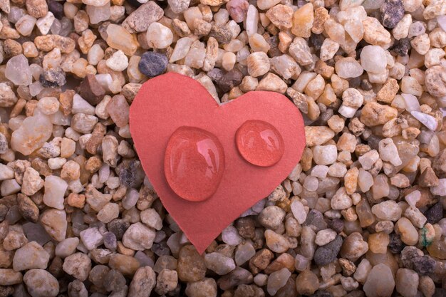 Gotas de agua en un papel en forma de corazón en la arena