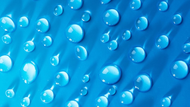 Gotas de agua sobre fondo azul Gotas abstractas de gel Cosméticos de suero facial