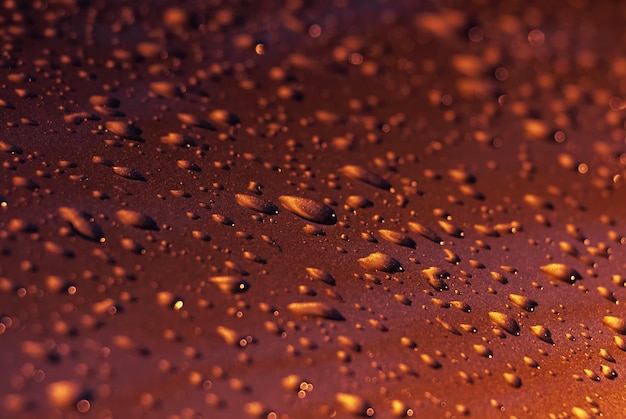 Gotas de agua sobre una superficie de metal rojo.