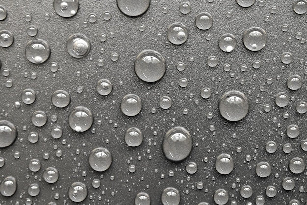 Gotas de agua sobre una superficie de plástico negro Sobre un fondo negro Vista superior